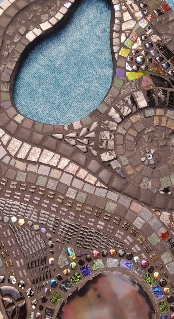 Black mosaic made with glass, stone and ceramic on a shaped base.